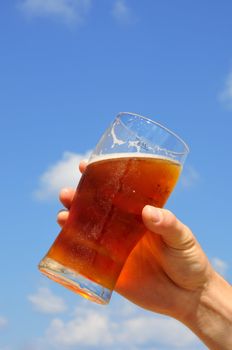 
	
Man holds in his hand a glass of beer on the background of the sky