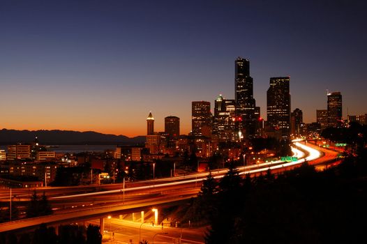 A beautifully illuminated painting like night shot of downtown Seattle with the freeways in foreground