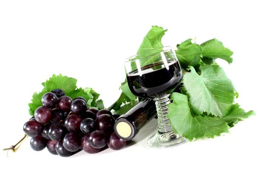 a bottle of red wine and fresh grapes on a white background