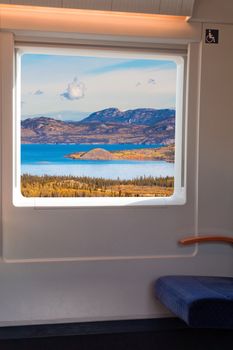 Interior view through window of high-speed train travelling in beautiful natural fall landscape.