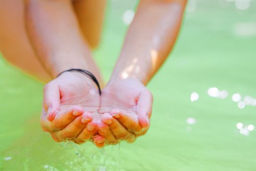 Woman's hands playing with fresh water