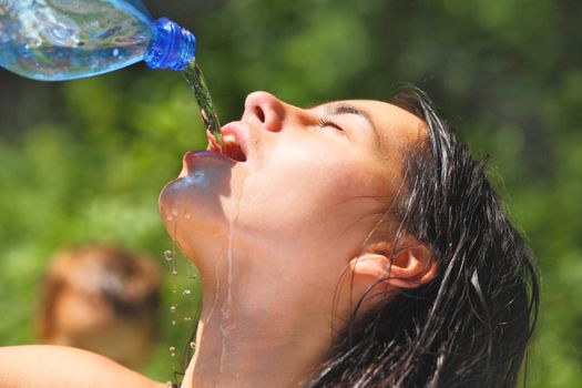 Young woman drinking water outdoors. She has a thirst