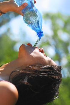 Young woman drinking water outdoors. She has a thirst. Side view