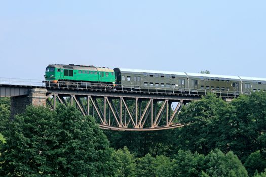 Passenger train passing through the big steel bridge

