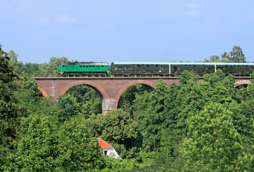 Passenger train passing through the big stone bridge
