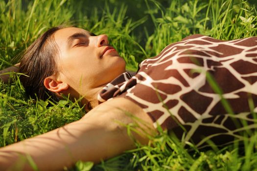 Beautiful young woman resting in green grass