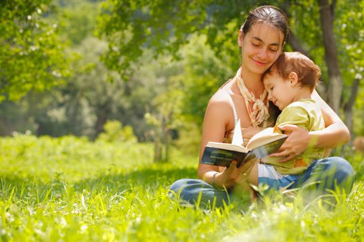 Happy mother and son reading a book outdoors