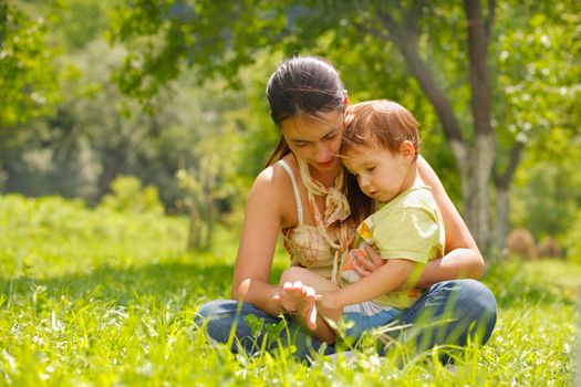 Happy mother and son sitting in a meadow