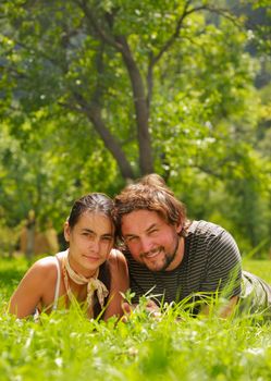 Young attractive couple smiling and lying on a grass