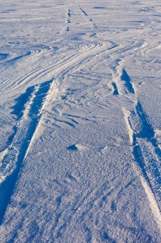 Snowdrift over vehicle tire tracks in deep snow.