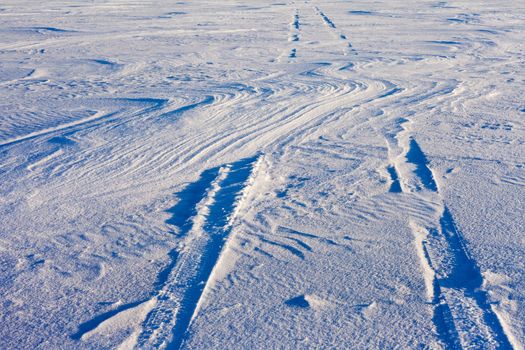 Snowdrift over vehicle tire tracks in deep snow.