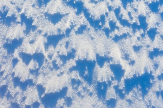 Windblown snow surface in bright sun, background texture pattern.