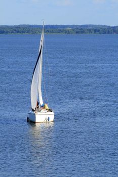 Yacht sailing on the lake under colorful sky
