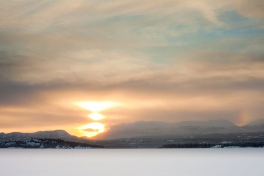 Early sunset over snowscape on cold foggy winterday.