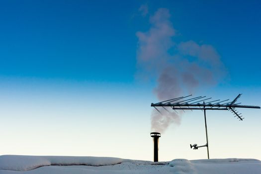 Smoking chimney of family home on a crispy cold clear winter day.