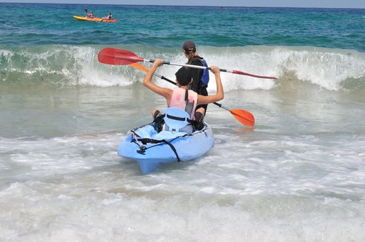 
	
Two young people want to swim away to sea kayaking, but hampered by a wave