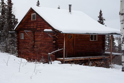 Snowflakes falling on cozy winter cabin inviting you to spend your Christmas holiday.