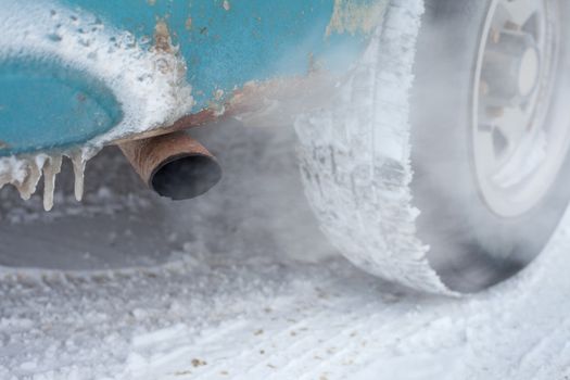 Exhaust pipe of idling car in cold winter conditions.