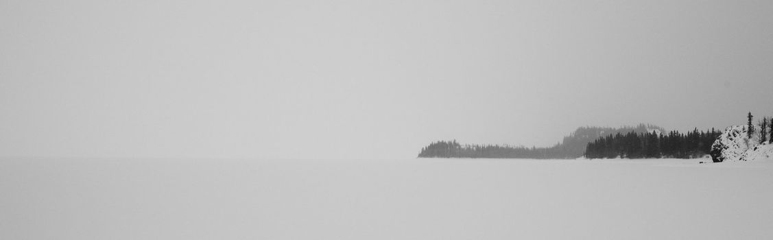 Bad winter weather windswept shoreline of frozen lake.