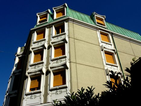 Original facade of a building with green roof and yello windows by beautiful weather