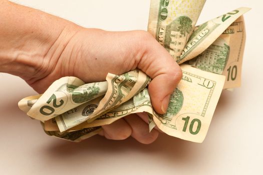 Fist crunching a bunch of American dollar banknotes symbolizing paper currency crisis.