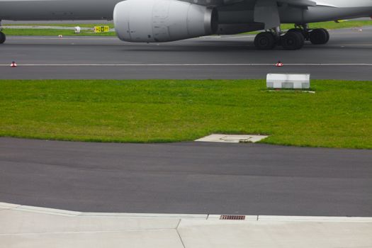 Aircraft landing gear and jet engine on runway ready for take-off.