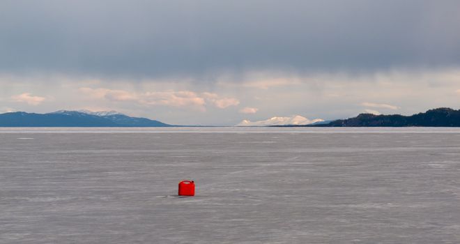 Red jerry-can full of gasoline on vast frozen Lake Laberge, Yukon Territory, Canada