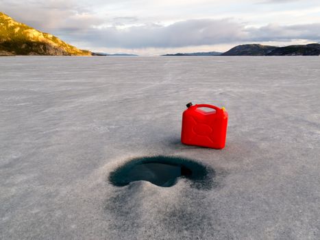 Red jerry-can full of gasoline on vast frozen Lake Laberge, Yukon Territory, Canada