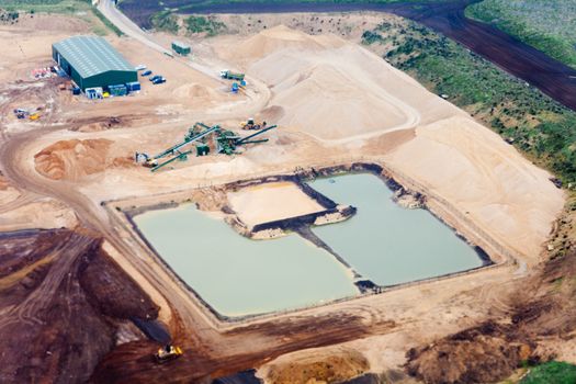 Aerial view of busy gravelpit operation with flooded dredging ponds.