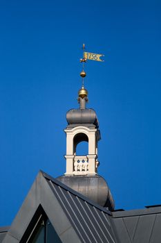 Small turret with metalic weather vane of Riga city hall against blue sky