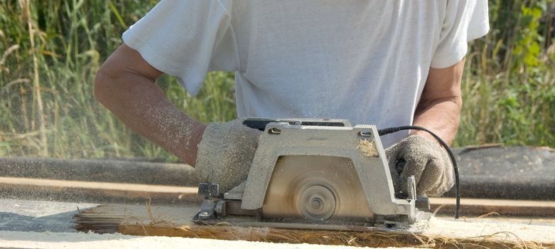 The man saws a board a circular power saw