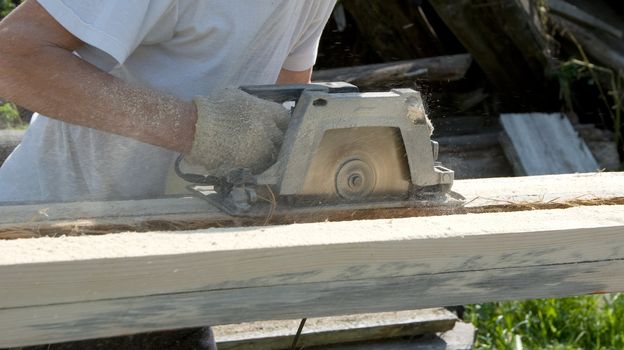 The man saws a board a circular power saw