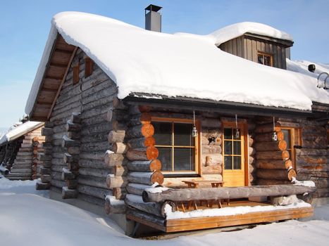 Traditional snow covered log cabin in a holiday resort in Lapland, Finland.