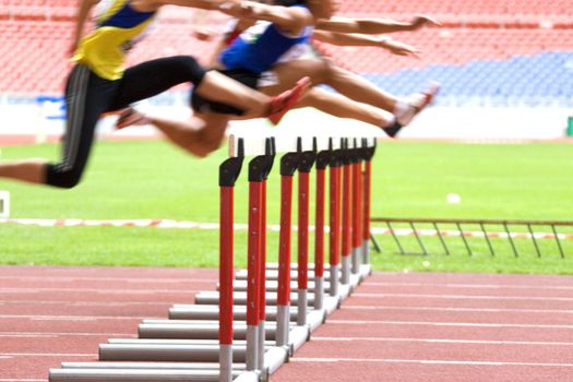 Image of hurdles in action at a stadium with intentional blurring to portray speed.