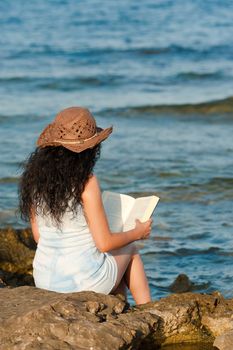 Woman ejoying a book with her feet in the water