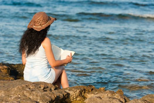 Woman ejoying a book with her feet in the water