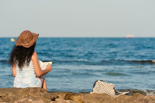 Woman ejoying a book with her feet in the water