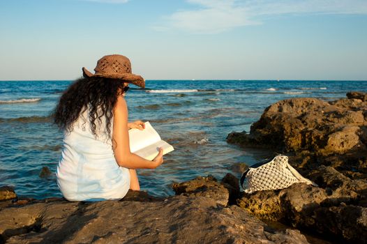 Woman ejoying a book with her feet in the water