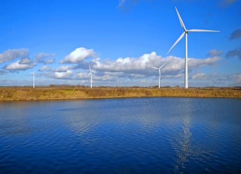 Wind Turbines and lake under a cloudy blue sky