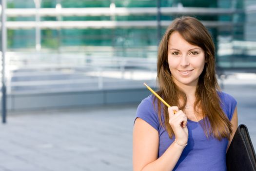 Pretty beautiful caucasian white girl pondering or thinking outside college school holding pencil