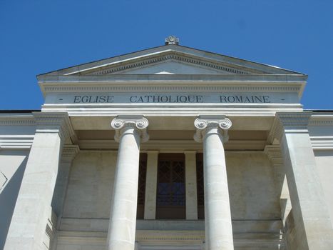 Facade of a white roman catholic church with pylons by sunny day.