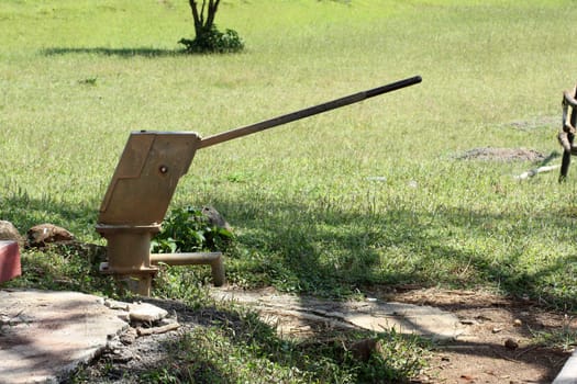 An old rusted water hand pump on an underground well in an Indian village.