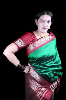 A beautiful Indian woman in a traditional green sari, on black studio background.