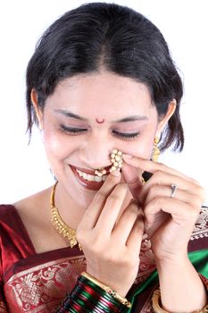 A beautiful traditional Indian woman adjusting her nosering, on white studio background.