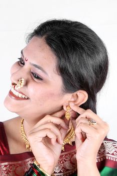 A traditional Indian woman wearing a gold earring, on white studio background.