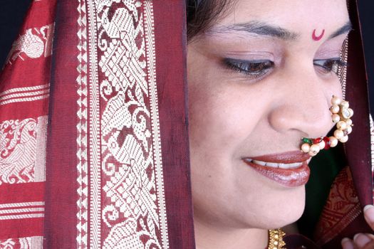 A portrait of traditional Indian woman in a green sari wearing a nosering.