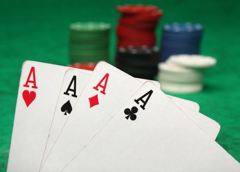 Four aces with gambling chips over green felt
