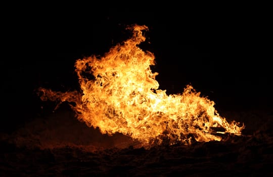 A raging bonfire burns on the beach.