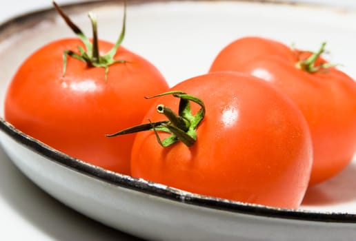 Three tomatoes in a old white plate