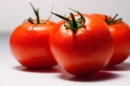 Three tomatoes on a light background